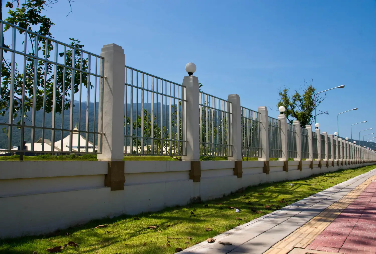 Aluminum fence with ornamental design and concrete base along a landscaped pathway, showcasing durability and aesthetic appeal for residential or commercial properties.