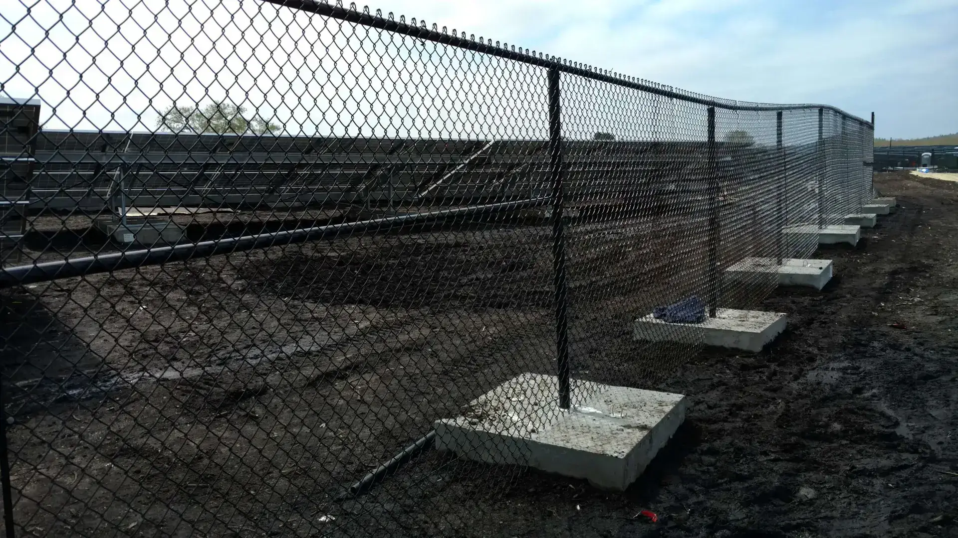 Olympic Fence Co. chain link fence installation in West Newbury, featuring black coated chain link and concrete footings.