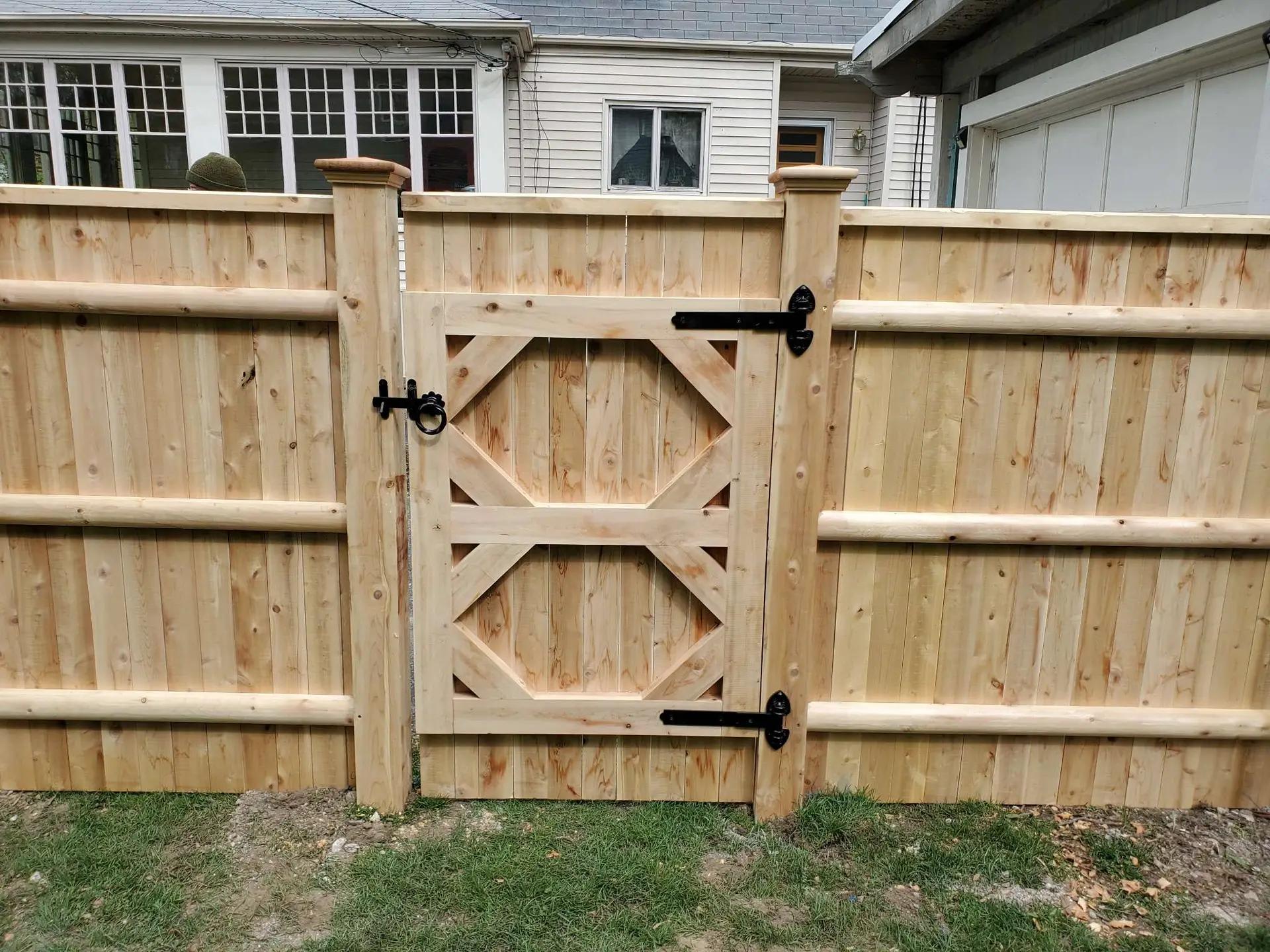 Cedar privacy fence with decorative gate installed by Olympic Fence Company in Groveland, MA, featuring a lifetime workmanship warranty.