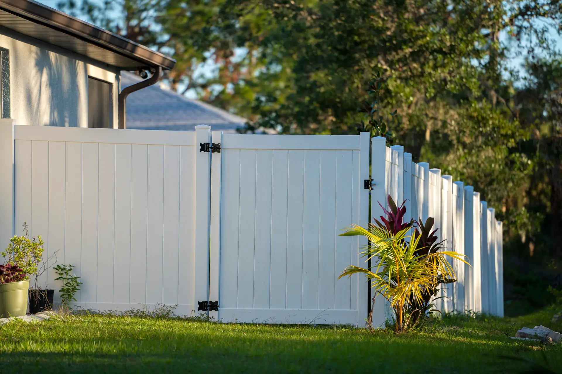 White vinyl privacy fence with heavy-duty panels, surrounded by green lawn and tropical plants, illustrating low-maintenance fencing ideal for coastal properties.