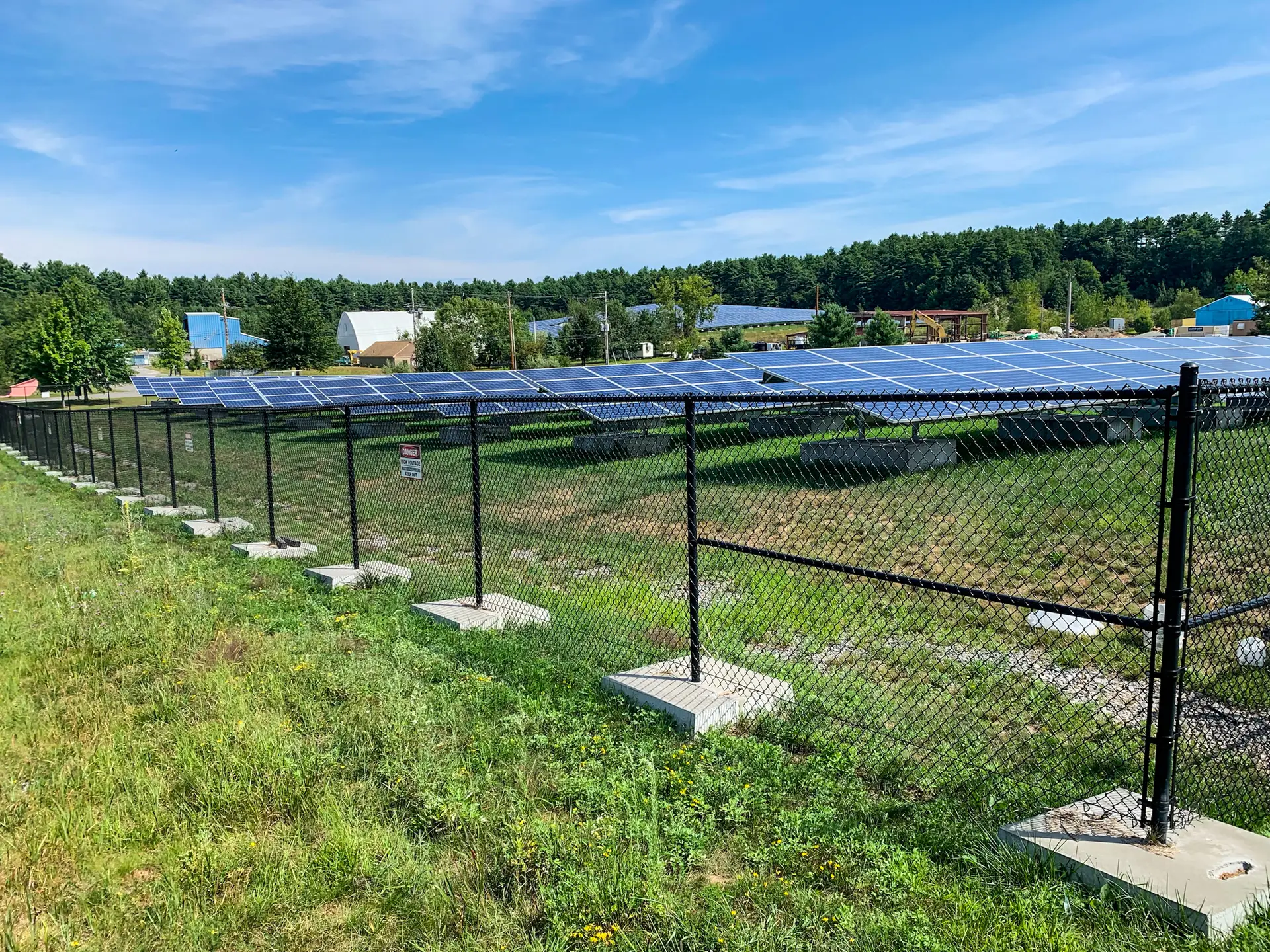 Black chain link fence installed by Olympic Fence Company securing a commercial solar panel field in West Newbury.