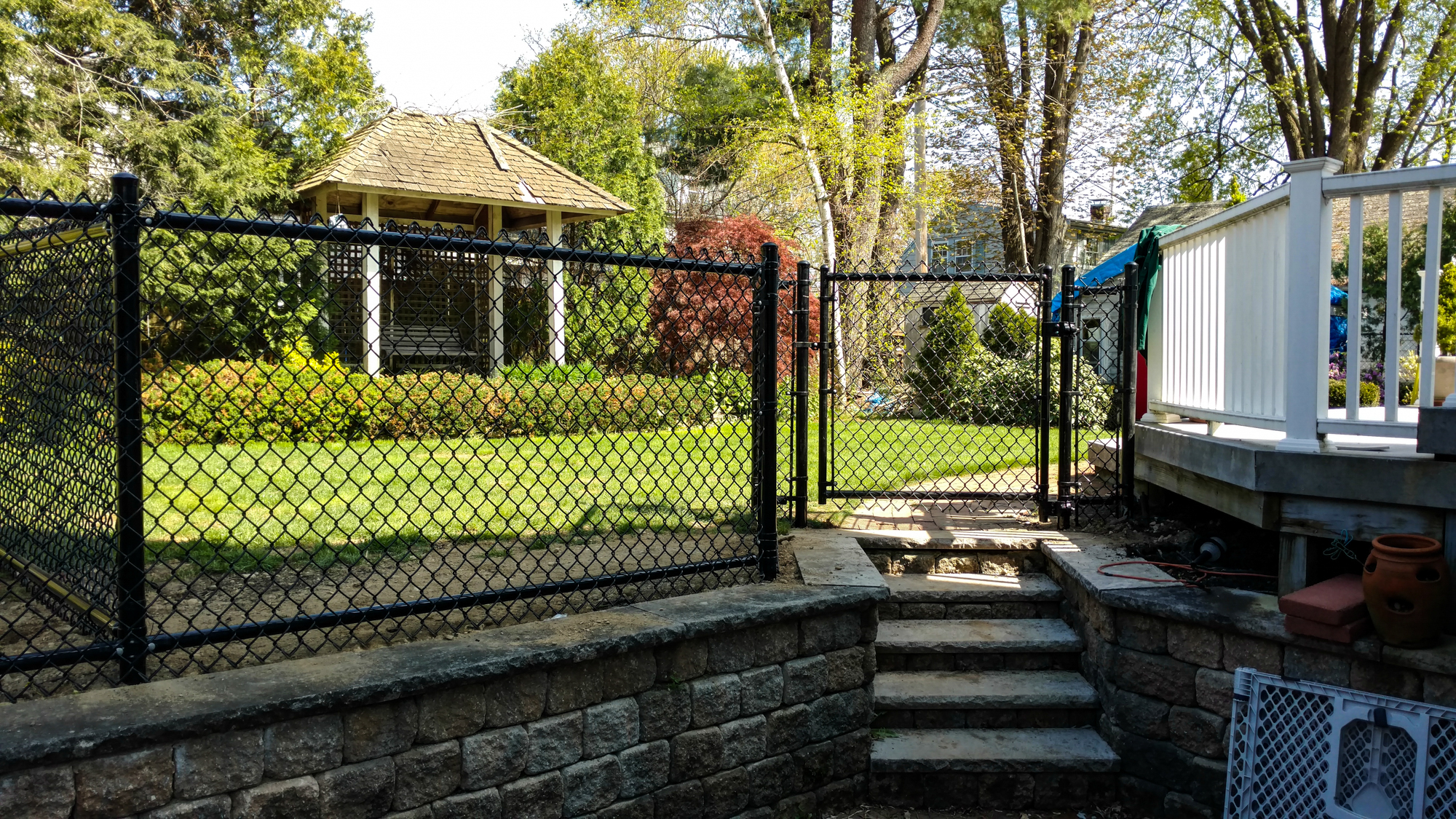 Chain link fence enclosing a well-maintained yard with a gazebo, surrounded by greenery, illustrating residential fencing options in Newburyport.