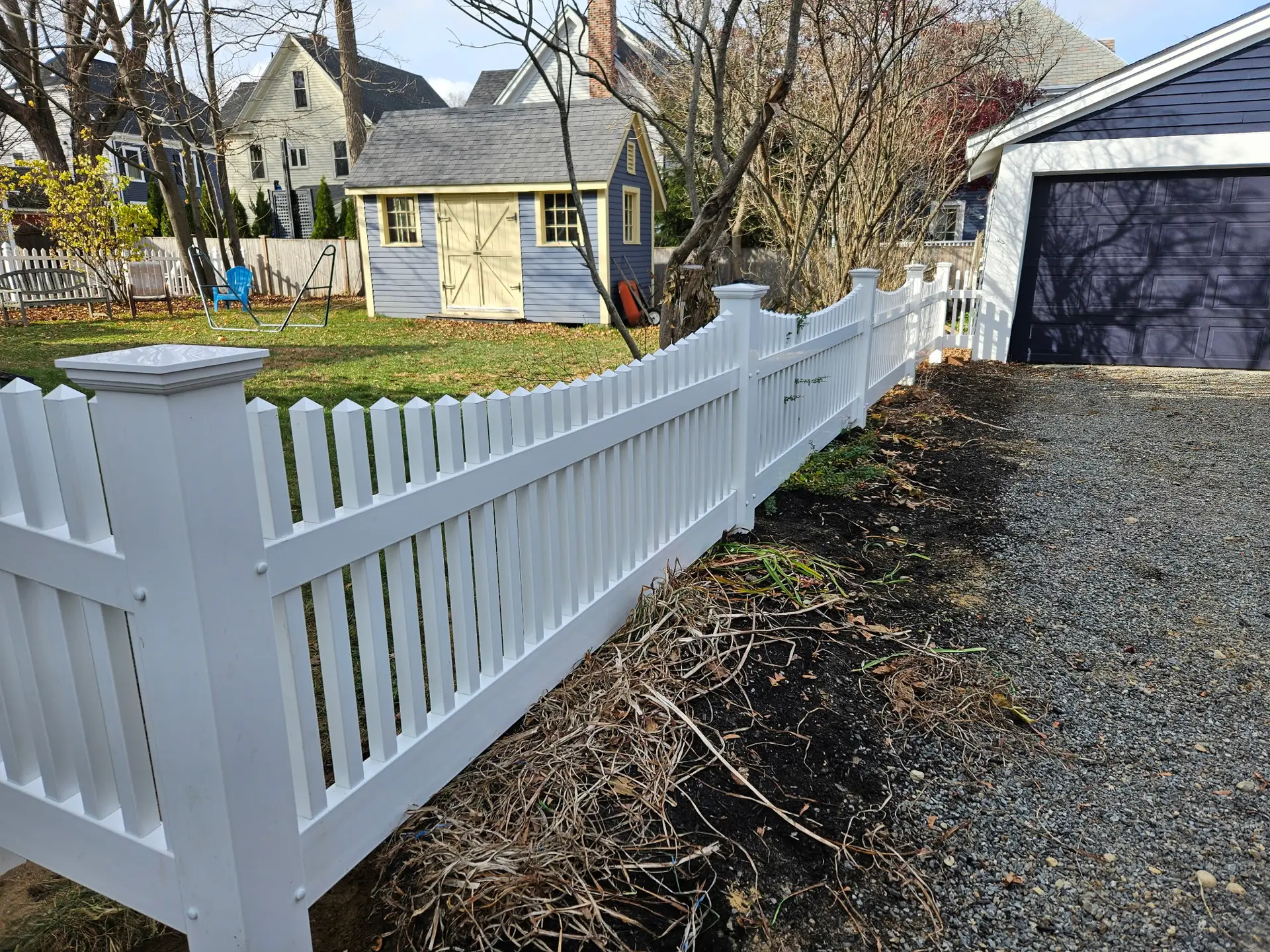 White scallop-top vinyl fence installed by Olympic Fence Company in West Newbury, Massachusetts.