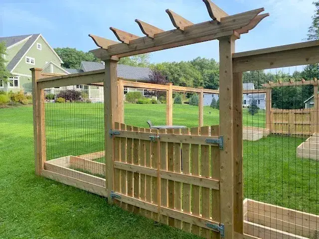 Wooden privacy fence with a gate and trellis, set in a grassy yard, showcasing a durable outdoor living space ideal for enhancing residential aesthetics.