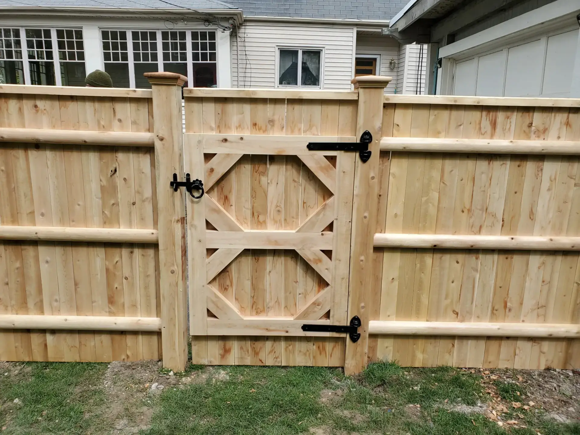 Wooden privacy fence with decorative gate, showcasing design elements suitable for enhancing outdoor living spaces in Massachusetts.