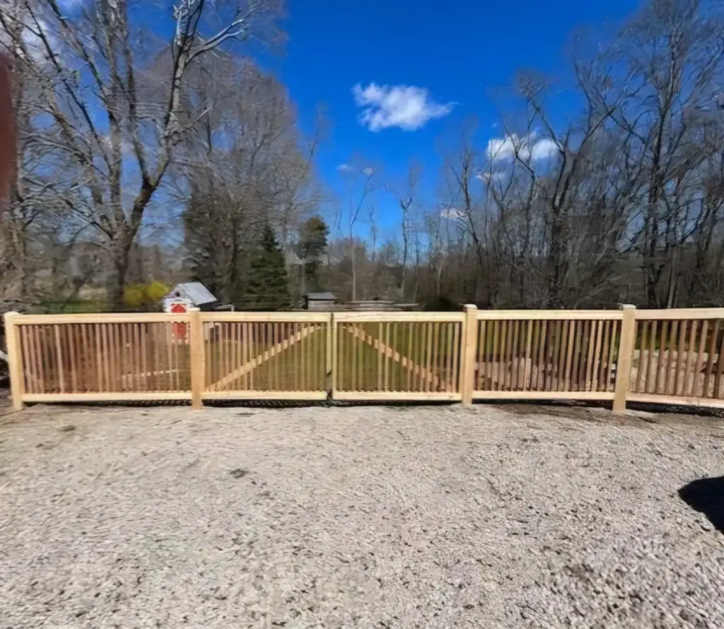 Wooden fence gate in a residential setting, surrounded by trees and blue sky, representing fencing solutions for homeowners in Newburyport, MA.